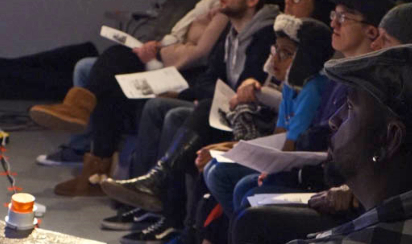 On Left prop of flashing light for deaf. It is a door bell, in right of picture a young audience in dark watching a performance