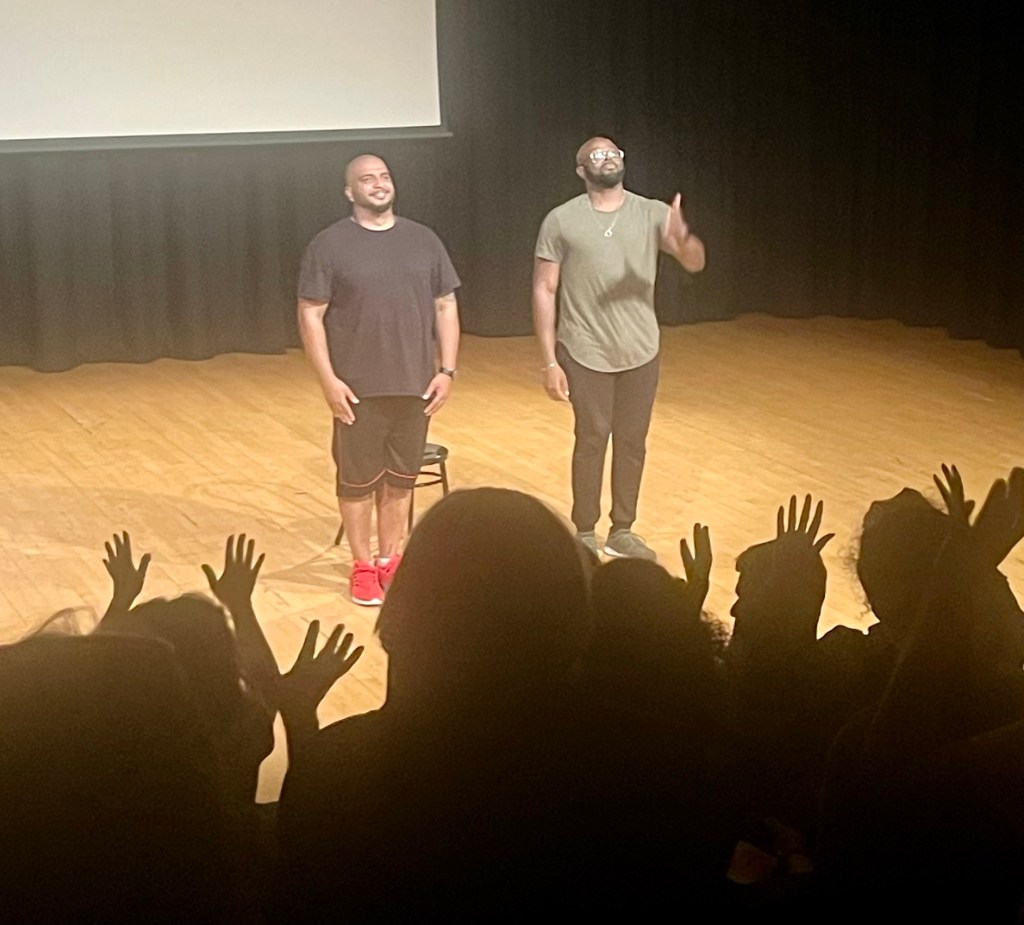 New work for All audiences, Two men bow after their performance, hand raised in the air  - applause